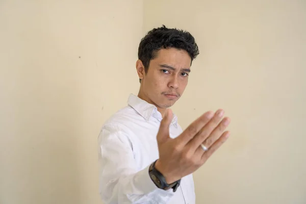 Genç Endonezyalı kıvırcık adam dövüş pozu veren beyaz elbiseler giyiyor. Bu fotoğraf, erkek ifadesi reklamcılığı ve moda yaşam tarzı için uygun..