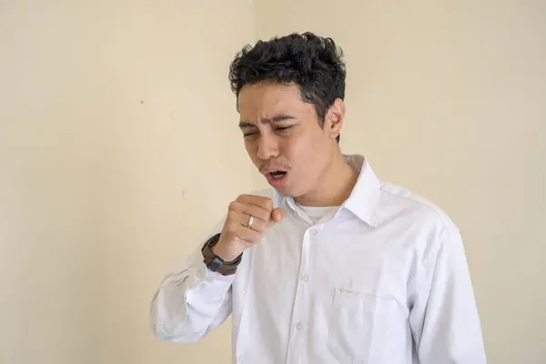 Young Indonesian curly man wear white clothes with cough pose. The photo is suitable to use for man expression advertising and fashion life style.