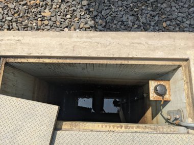 Aşağıdaki karanlık derinlikleri açığa çıkaran açık bir rögar kapağına bakan yakın çekim görüntüsü..