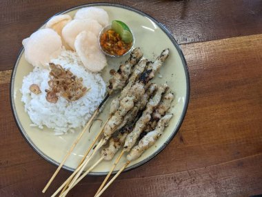 Bir tabak Endonezya tavuğu, pirinç, sambal ve kraker ile servis edilir..