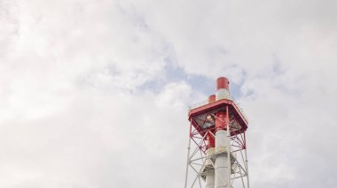 Bulutlu bir gökyüzüne karşı uzun bir bacanın yakın çekimi..