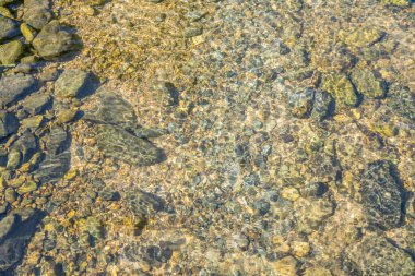 Pürüzsüz taş ve çakıl taşlarının üzerinden akan temiz suyu gösteren bir nehir yatağını kapatın. Su o kadar berrak ki, nehir yatağının dibini görebilirsin..