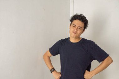 Meraklı bir ifadeye sahip genç bir adamın portresi, beyaz bir arka plana bakıyor. O, siyah bir tişört giydi..