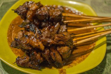 Izgara et parlıyor ve zengin fıstık sosu şişlerin üzerine cömertçe dökülüyor..