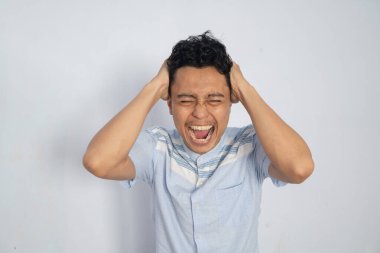 Genç bir adam kafasını tutarken yoğun bir hayal kırıklığı ve stres gösterir..