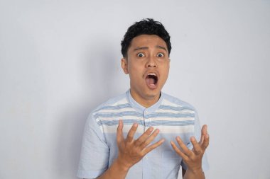 Şaşırmış genç bir adam, geniş gözlü ve ellerini kaldırmış, şok olduğunu ifade ediyor..