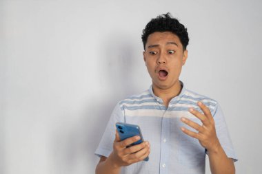 Genç bir adam telefonunu kontrol ederken şaşkınlık içinde, şaşkınlık dolu bir anı yakalıyor..