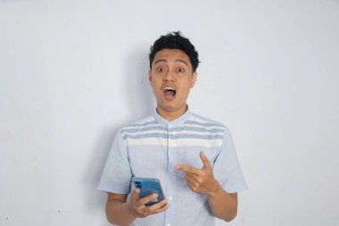 Şaşırmış bir genç adam elinde akıllı bir telefonla sevinçle tepki veriyor..