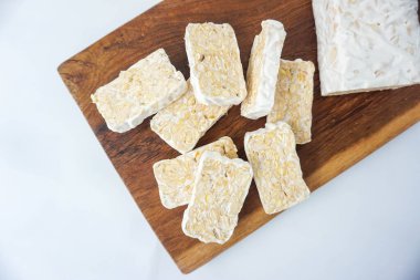 Raw Tempeh veya Tempe. Ahşap Arkaplanda Tempeh Dilimleri ve beyaz izole edilmiş. Metin için Boşluğu Kopyala