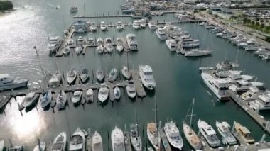 This 4K aerial drone footage is a true visual masterpiece, showcasing a collection of moored yachts and boats in the crystal clear turquoise waters. The footage is shot from high above the water, providing a bird's eye view of the vessels.