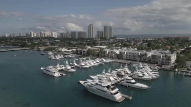 This 4K aerial drone footage is a true visual masterpiece, showcasing a collection of moored yachts and boats in the crystal clear turquoise waters. The footage is shot from high above the water, providing a bird's eye view of the vessels.