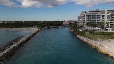 Experience the natural beauty of Boca Inlet, Florida from an aerial perspective with this 4K video. The footage captures the crystal clear water, sandy beaches, and boats and yachts navigating the waterway.