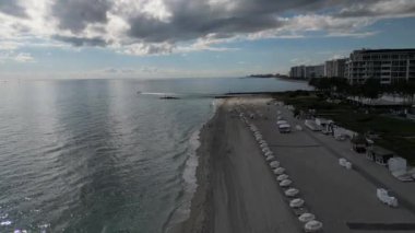 This 4K aerial video captures the vibrant colors of umbrellas on a Florida beach. The footage offers a bird's-eye view of the area, showcasing the umbrellas' design, colors, and arrangement.