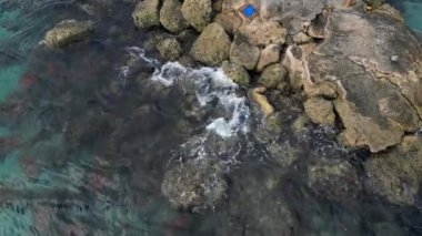 Experience the power of nature with this 4K aerial video of waves crashing on rocks. The footage offers a bird's-eye view of the area, showcasing the mesmerizing movement of the waves.