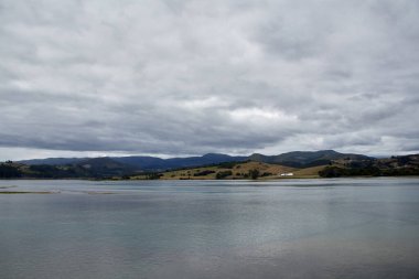 Sea of gray tones under a cloudy sky with mountains in the background. Copyspace. Horizontal photography.