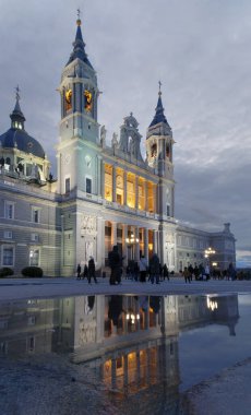 Puddle on the pavement in which the neoclassical doorway of the Almudena Cathedral is reflected in a night view. Vertical photography.