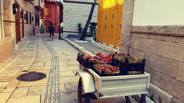 wheelbarrow full of strawberry crates on an old street