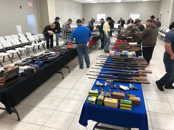 Bir müzayedede potansiyel alıcılar için birden fazla tüfek sergileniyor..