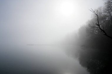 Gölde iskeleli bir manzara var. Sabah sisli doğa..