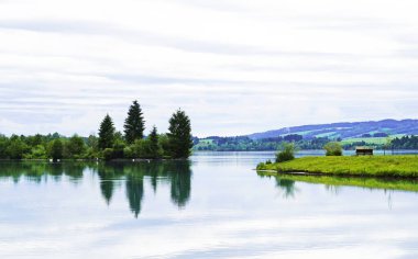 Lechbruck 'taki Lech rezervuarı. Etrafı doğayla çevrili göl manzarası. Sudaki yansıma..