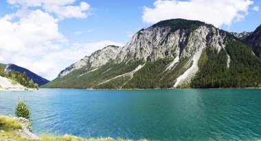 Tyrol, Avusturya 'daki Plansee' de manzara. Turkuaz renkli göl çevresi ve dağlarla çevrili..