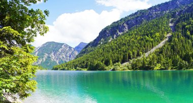 Tyrol, Avusturya 'daki Plansee' de manzara. Turkuaz renkli göl çevresi ve dağlarla çevrili..