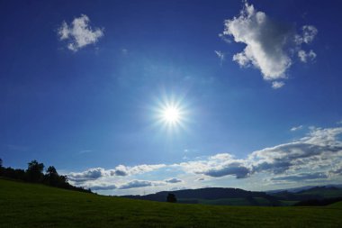 Yıldız şeklinde güneş. Sauerland manzarası hafif bulutlu gökyüzü ve yeşil tepeler.