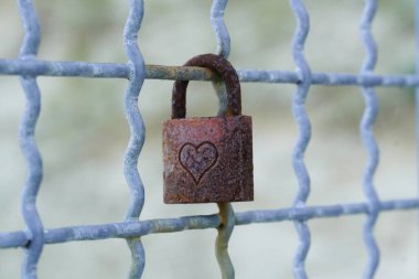 Metal bir ızgarada paslanmış aşk kilidi.