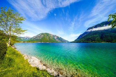 Tyrol 'daki Achensee Gölü manzarası. Turkuaz göldeki doğa ve arka planda bir dağ manzarası. Avusturya 'da Achental.