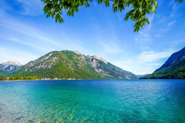 Tyrol 'daki Achensee Gölü manzarası. Turkuaz göldeki doğa ve arka planda bir dağ manzarası. Avusturya 'da Achental.