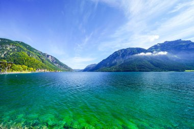 Tyrol 'daki Achensee Gölü manzarası. Turkuaz göldeki doğa ve arka planda bir dağ manzarası. Avusturya 'da Achental.