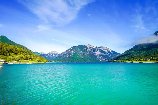Tyrol 'daki Achensee Gölü manzarası. Turkuaz göldeki doğa ve arka planda bir dağ manzarası. Avusturya 'da Achental.