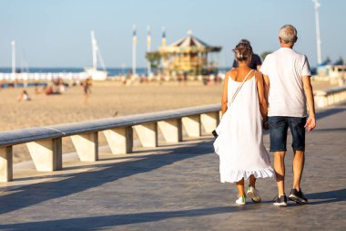 Yaşlı bir çift sahilde geziniyor.