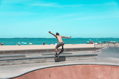 Genç adam kaykay parkında kayıyor.