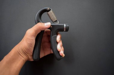 Hand exercising, squeezing a handgrip, man gripping hand exercise gripper.
