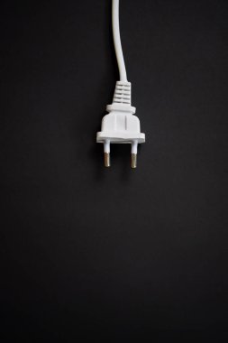 Electric European plug isolated on black background. White power cable with plug. Power cord close-up