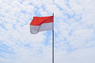 Indonesian Flag, Red and White, waving in the wind with blue sky background