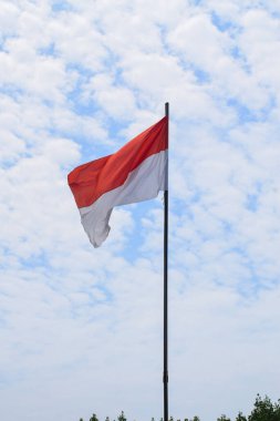 Indonesian Flag, Red and White, waving in the wind with blue sky background