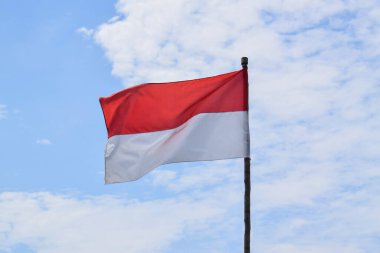 Indonesian Flag, Red and White, waving in the wind with blue sky background