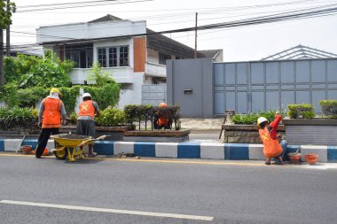 Pasuruan - November 17, 2022 : Workers repairing traffic lane dividers and separators made of concrete on asphalt roads