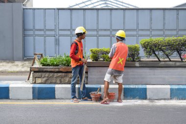 Pasuruan - November 17, 2022 : Workers repairing traffic lane dividers and separators made of concrete on asphalt roads