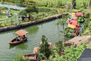 Malang, 24 Desember 2022 - Row boat tour Wooden Boat With Pedals with beautiful mountains view. At a tourist spot while on vacation