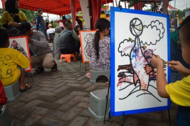 Pandaan, 15 January 2023 - A child with a brush and watercolors in his hands is learning to draw on a canvas. Child development and Education concept