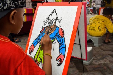 Pandaan, 15 January 2023 - A child with a brush and watercolors in his hands is learning to draw on a canvas. Child development and Education concept