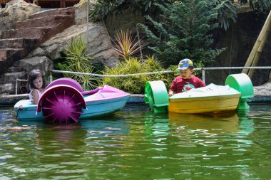 Malang, 24 Desember 2022 - Children driving children's water boats on the water.