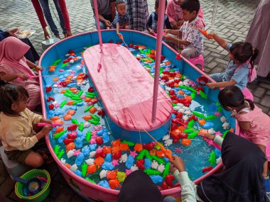 Pandaan, 15 January 2023 - Fishing in the paddling pool. Children's toys in the pool. Toy fish fishing rod. Little Boy Have Fun Fishing Carnival Festival Amusement For Kids