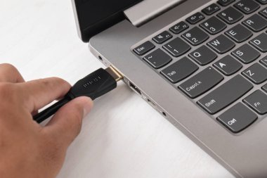 Adam siyah HDMI kablosunu beyaz arkaplandaki modern dizüstü bilgisayarın HDMI portuna bağlıyor