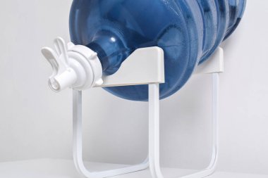 Beyaz arka planda izole edilmiş musluğu olan bir rafta duran plastik bir galon. Büyük su şişeli su dağıtıcısı.
