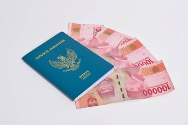 Beyaz arka planda 100.000 rupia 'lık yığınla Endonezya pasaportu.