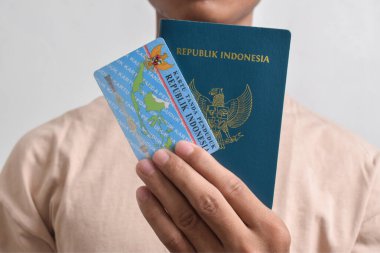 Pasuruan, Endonezya - 2 Mayıs 2024: Endonezya pasaportu ve Endonezya kimlik kartı tutan adam beyaz arka planda izole edildi